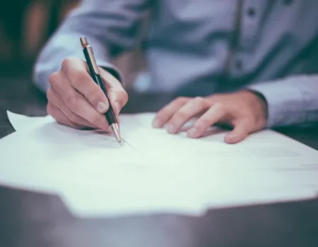 Person signing legal documents related to a car accident settlement.