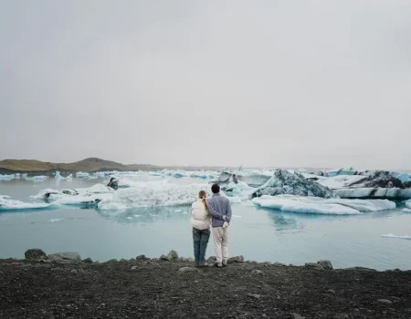 Couple embracing by a serene winter lake with floating icebergs.