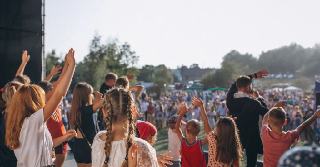 Crowd enjoying a live music performance at Lilapalooza festival with colorful stage lights and art installations in the background.