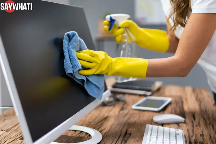 Office cleaning staff disinfecting keyboard and wiping desk surface in workplace